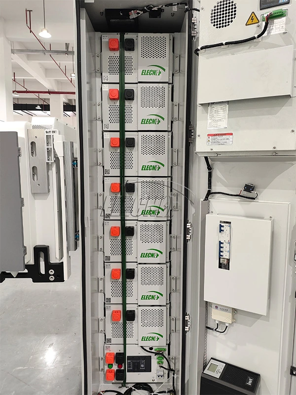 Open cabinet showing vertically arranged battery modules, cabling and door-mounted equipment