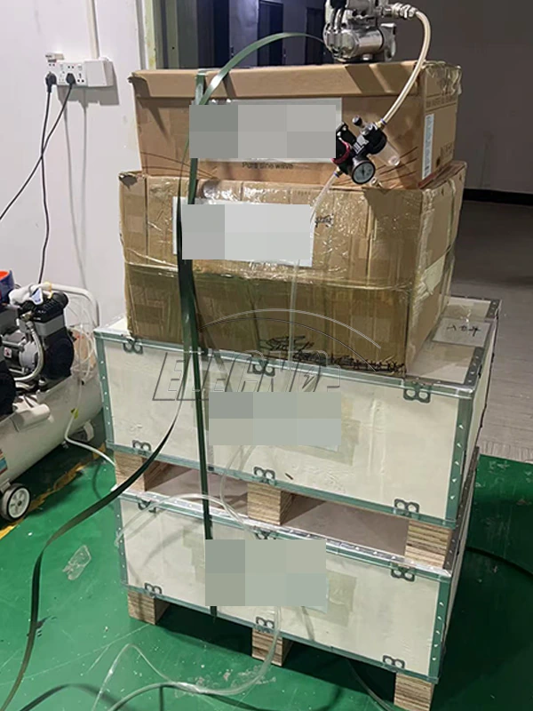 Cartons and protective cases secured with straps on a pallet, with customer labels obscured